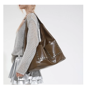 Detailed view of glossy brown rivet tote bag shown on model with punk biker style