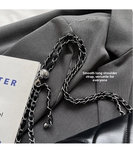Detail of adjustable metal ball on a black quilted leather bag with chain strap