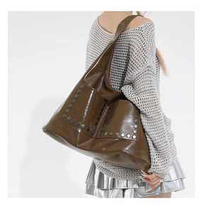 Detail view of large brown glossy tote bag with hexagonal studs on side