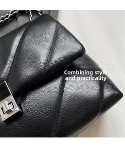 Close-up of black quilted leather texture with silver metal twist lock and chain strap