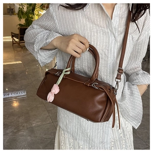 Close-up of brown litchi pattern Boston bag with elegant tulip charm on a female model