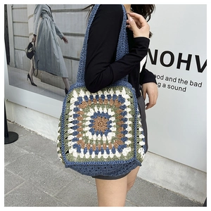 Detail of blue crochet tote bag with colorful granny square patterns and wide shoulder strap