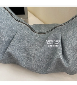 Close-up of blue denim crescent bag showing soft textured fabric and zipper detail