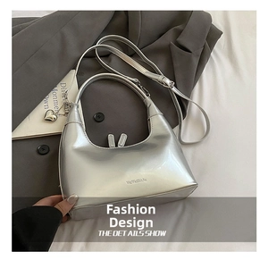 Detail of silver metallic crescent bag with heart charm and brand logo on white fabric