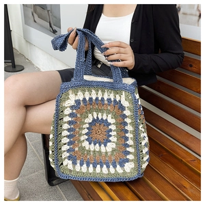 Close-up of handmade crochet tote bag featuring colorful granny square patterns on a bench
