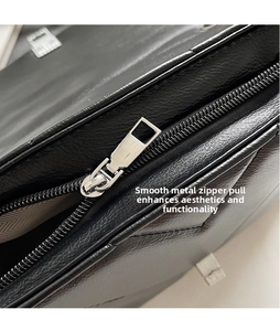 Detailed close-up of smooth silver zipper pull on black quilted crossbody bag