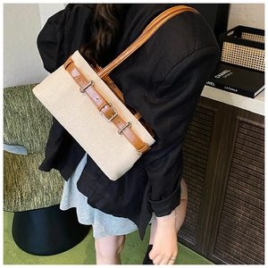 Détail d'un sac à bandoulière en paille tressée avec lanières en cuir marron porté