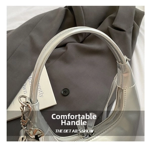 Detail of silver metallic hobo bag featuring heart pendant and smooth leather handle