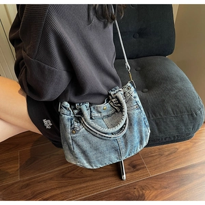 Dettaglio borsa tote in denim lavato vintage con catena in metallo e manico in denim