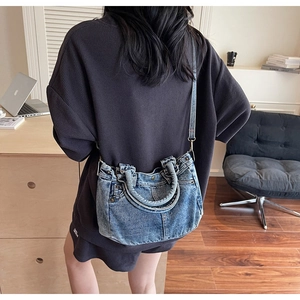 Dettaglio della borsa tote in denim lavato vintage con design a tasca e manici in pelle
