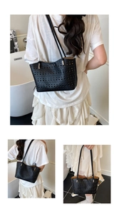 Detalle de la textura de cuero negro perforado y herrajes metálicos plateados del bolso tote