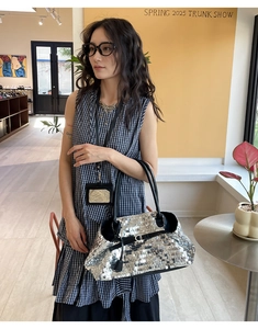 Close-up of silver sequin tote bag with black leather handles in a boutique setting