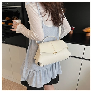 Close-up of creamy white lychee grain leather shoulder bag with gold metal buckle detail