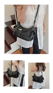 Detail view of black glossy patent leather shoulder bag with multiple silver zipper pockets