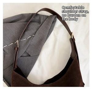 Close-up of matte dark brown suede tote bag featuring adjustable gold buckle and leather strap
