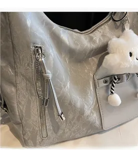 Detail of silver pleated handbag with smooth zipper and white plush sheep charm