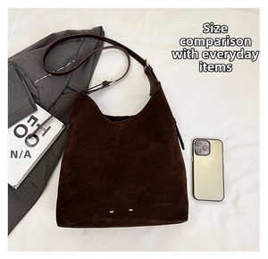 Detail of dark brown matte suede hobo bag featuring adjustable strap and metallic studs