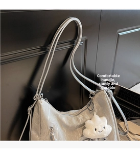 Detail of silver pleated shoulder bag with a cute white cloud plush pendant accessory