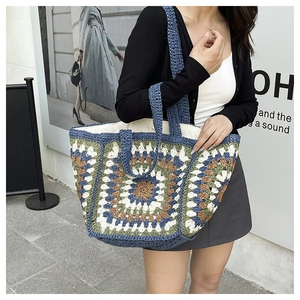 Detail of bohemian crochet tote bag with colorful granny square patterns and woven strap
