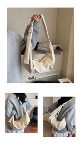 Close-up of beige crescent hobo bag featuring knotted shoulder strap and zipper closure