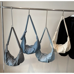 Detail view of four pleated croissant bags in charcoal, denim blue, grey, and cream colors