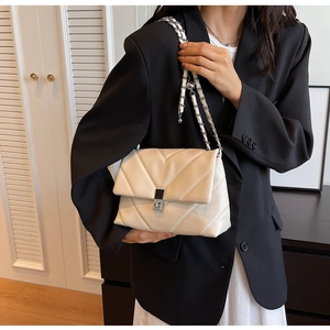 Detail der beigen Stepptasche mit Metallkettenriemen und quadratischem Drehverschluss
