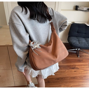 Detail of caramel woven tote bag with silver star charm and adjustable wide shoulder strap