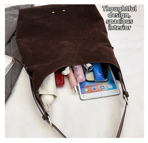 Detail view of large capacity interior of dark brown suede tote bag with daily items