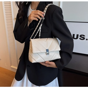 Close-up of a white V-quilted leather chain bag with silver twist lock on model