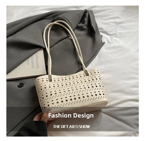 Detalle del bolso tote beige con cortes láser geométricos y asas finas sobre fondo neutro