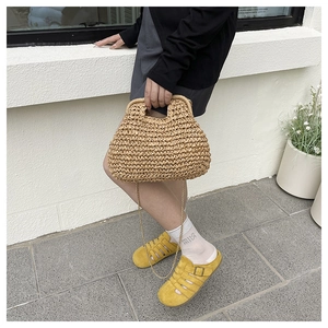 Détail du sac à main en paille tressée avec texture naturelle et chaîne dorée élégante