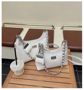 Detail van witte leren schoudertas met zilveren metalen slot en mini-portemonnee