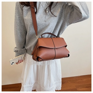 Brown leather handbag with wide shoulder strap shown on model for size and style reference