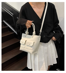 Detail of white crocodile texture handbag with knotted handle and dual pockets