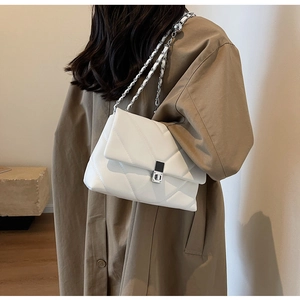 Gros plan d'un sac bandoulière blanc matelassé avec chaîne argentée sur un modèle