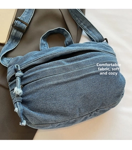 Detailed close-up showing the soft washed denim fabric texture and pleated design of the bag