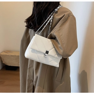 White quilted chain shoulder bag with silver square lock worn by model in minimalist setting