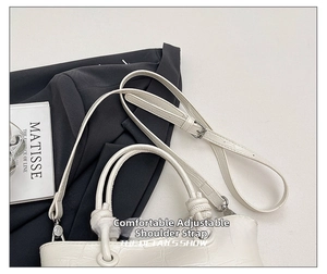 Detail showing white crocodile texture handbag with adjustable strap and dual handles