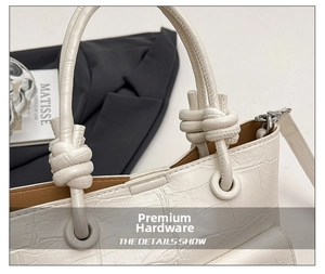 Detail of white crocodile embossed handbag with unique knot handle and silver hardware