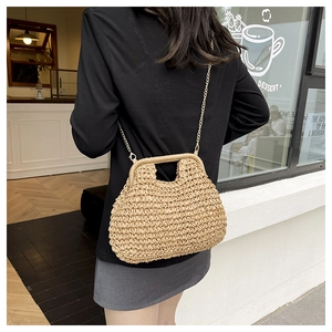 Detail of hand-woven straw bag with gold chain strap for summer beach vacation style