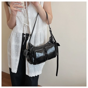 Model wearing a glossy black Y2K style shoulder bag with multiple functional zip pockets
