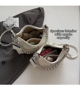 Detailweergave van de ruime binnenkant van een witte handtas met metalen kettingriem