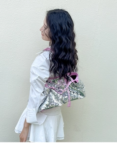 Dettaglio della borsa tote con paillettes argento, finiture in pelle rosa e fiocco
