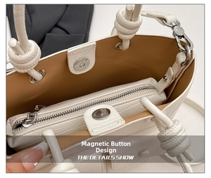 Close-up of white crocodile pattern handbag featuring a magnetic snap button and zipper closure