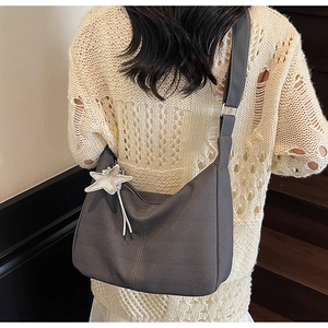 Detail of grey chevron textured crossbody bag with a white star charm on a wide strap