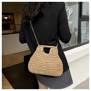 Detail of hand-woven straw shoulder bag with elegant gold chain strap on a model