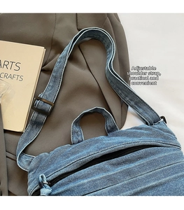 Detail of blue denim tote bag with adjustable black strap and zipper on brown blazer