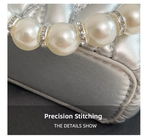 Close-up of quilted silver handbag showing neat stitching and pearl bead handle