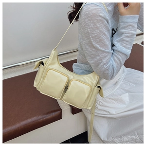 Detail of light yellow multi-pocket shoulder bag in soft leather on female model