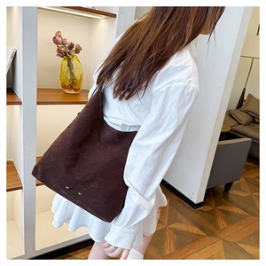 Detail of deep brown suede tote bag with dual gold studs and spacious interior